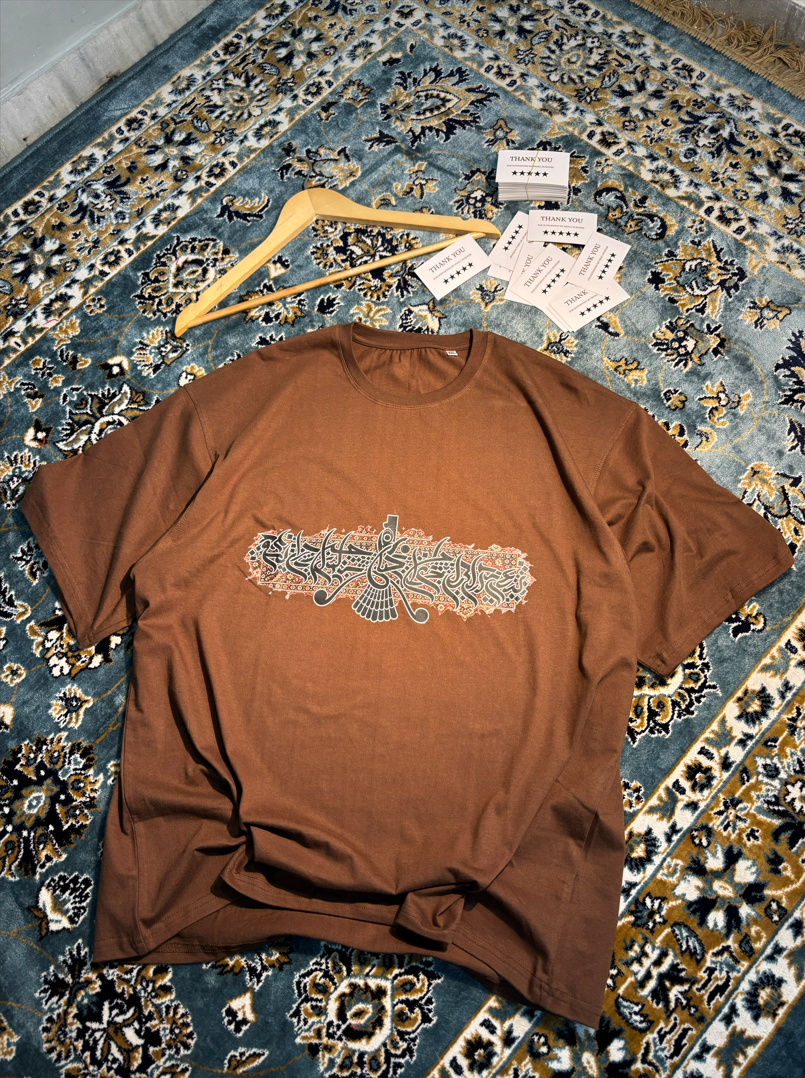 Persian Calligraphy Oversized Tee Brown – flat lay on rug angle 2