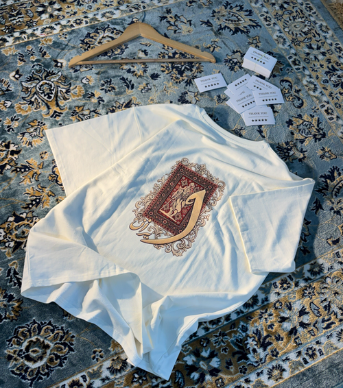 Persian Calligraphy White Oversized Tee – flat lay on Persian rug full view